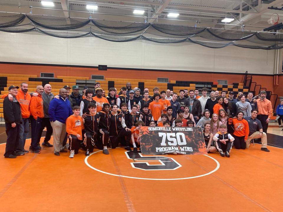 The Somerville wrestling team poses with alumni members after defeating Belvidere on Jan. 3, 2023, for the program’s 750th career win.