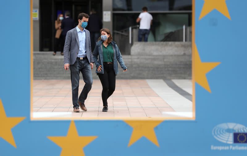 People wearing protective masks walk past the European Parliament headquarters amid the coronavirus disease (COVID-19) outbreak in Brussels