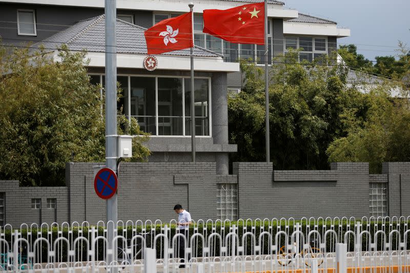 Man walks past Chinese and Hong Kong flags in Beijing