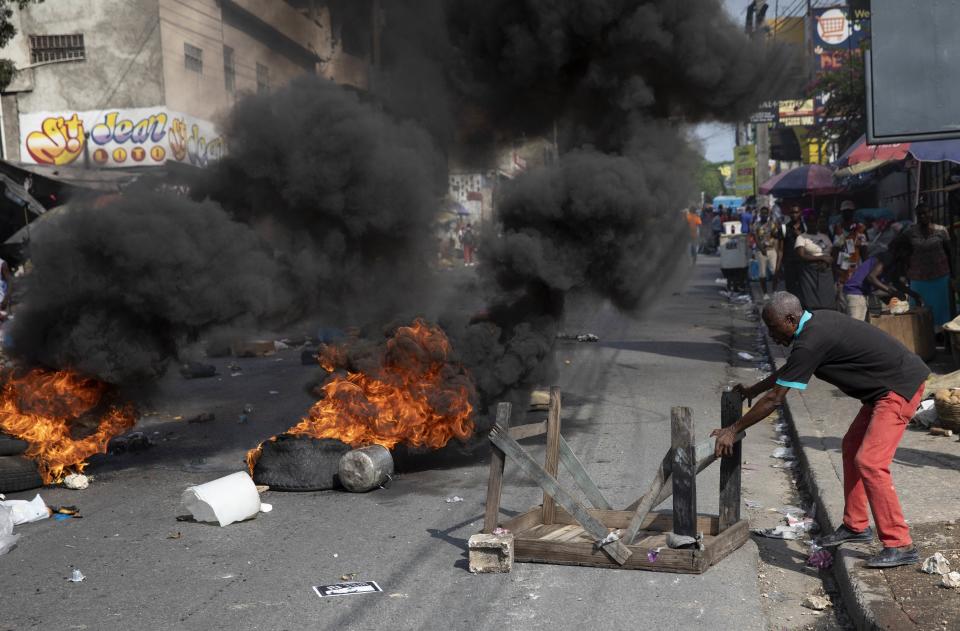 A man blocks an avenue with a table during a protest organized by friends and relatives of Biana Velizaire, who was kidnapped and held for several days by gang members, in Port-au-Prince, Haiti, Monday, Sept. 27, 2021. Haitian police on Monday launched a special operation in response to the recent surge of kidnappings conducted by gangs. (AP Photo/Rodrigo Abd)