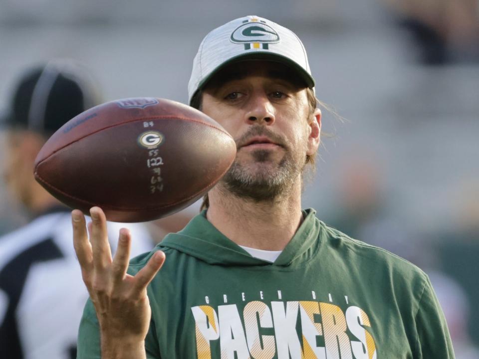 Aaron Rodgers holds a football during warmups before a 2021 preseason game.