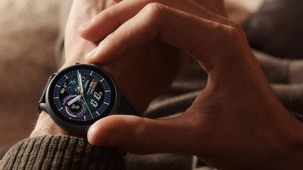  Fossil Gen 6 Wear OS watch worn on left wrist with user preparing to press a button. 