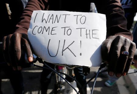 A migrant holds a placard which reads "I want to come to the U.K." on his bicycle at the makeshift camp called "The New Jungle" in Calais, France, September 19, 2015. REUTERS/ Regis Duvignau