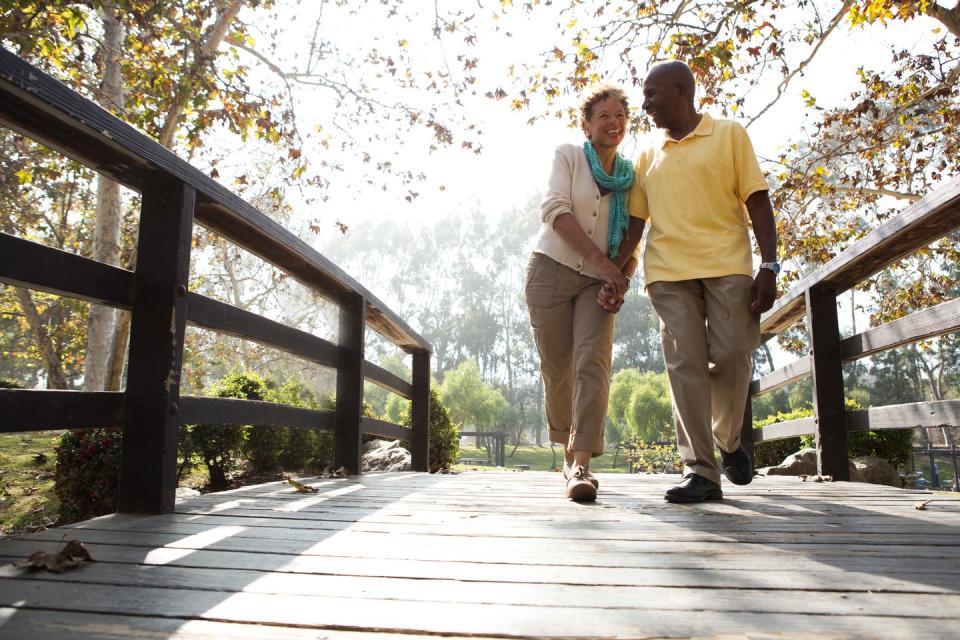 senior couple walking on footbridge in park