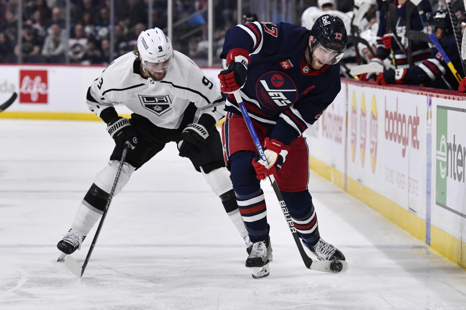 Winnipeg Jets' Adam Lowry shoots the puck as he is checked by Los Angeles Kings' Adrian Kempe (9)during the second period of an NHL hockey game in Winnipeg, Manitoba, on Tuesday, Feb. 28, 2023. (Fred Greenslade/The Canadian Press via AP)