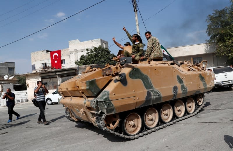 Turkey-backed Syrian rebel fighters on an armoured personnel carrier react as they drive to cross into Syrian town of Tal Abyad