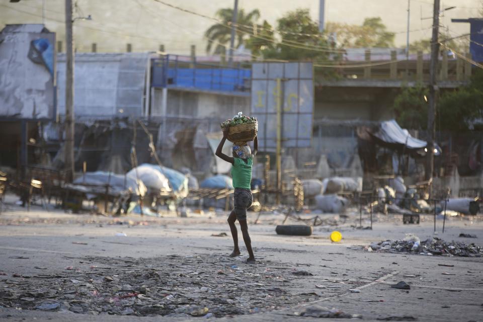 A woman crosses a street after clashes between police and gunmen at the Portail neighborhood of Port-au-Prince, Haiti, Thursday, Feb. 29, 2024. Gunmen shot at the international airport and other targets in a wave of violence that forced businesses, government agencies and schools to close early. (AP Photo/Odelyn Joseph)