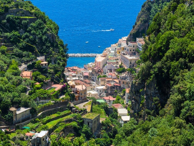 Colorful houses nestled in tree-covered mountains.