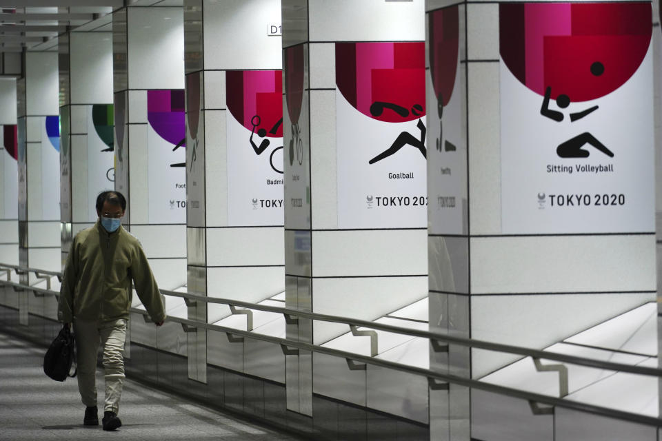 A man wearing a protective mask to help curb the spread of the coronavirus walks near banners of the Tokyo 2020 Olympics and Paralympics in Tokyo Tuesday, Jan. 19, 2021. The Tokyo Olympics are to open in six months on July 23. Interestingly, Tokyo organizers have no public program planned to mark the milestone. There is too much uncertainty for that right now. (AP Photo/Eugene Hoshiko)