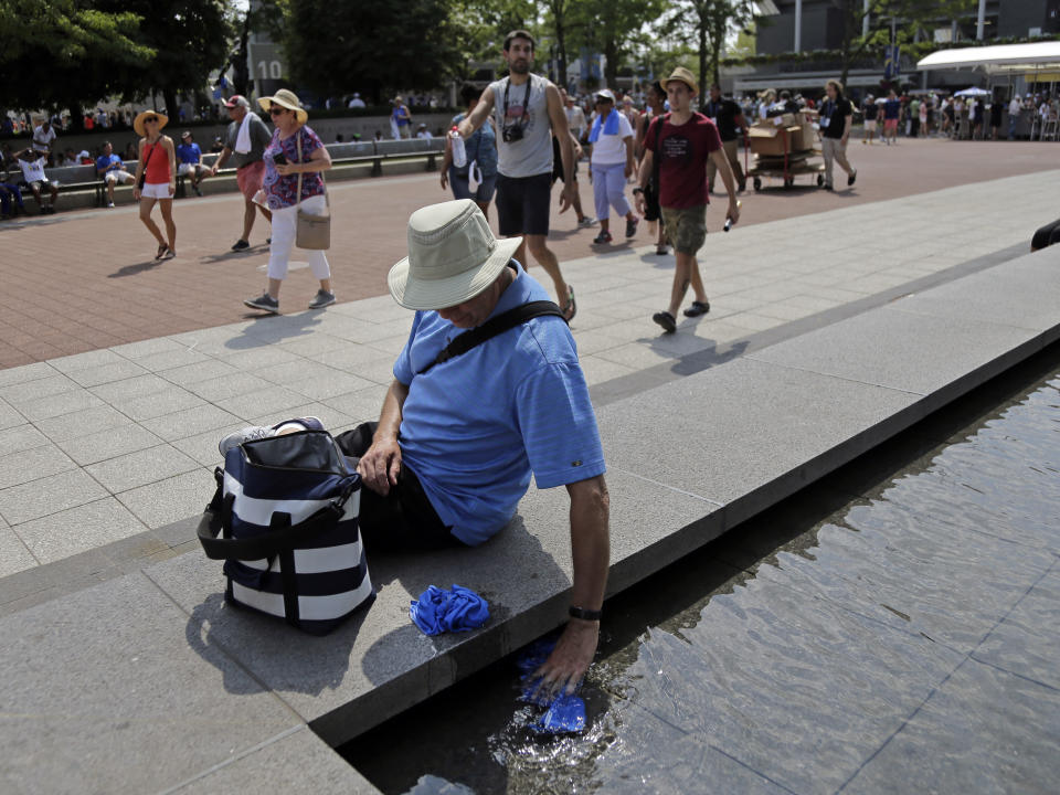 Doug Cronk dips a towel into a fountain outside of Arthur Ashe Stadium during the second round of the U.S. Open tennis tournament, Wednesday, Aug. 29, 2018, in New York. (AP Photo/Seth Wenig)