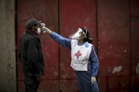 FILE - In this June 6, 2020 file photo, a Red Cross volunteer measures the temperature of man inside the Fraga slum, during a government-ordered lockdown to curb the spread of the new coronavirus, in Buenos Aires, Argentina. Argentina reached 1 million confirmed coronavirus cases on Monday, Oct. 19, 2020, according to the Ministry of Health. (AP Photo/Natacha Pisarenko, File)