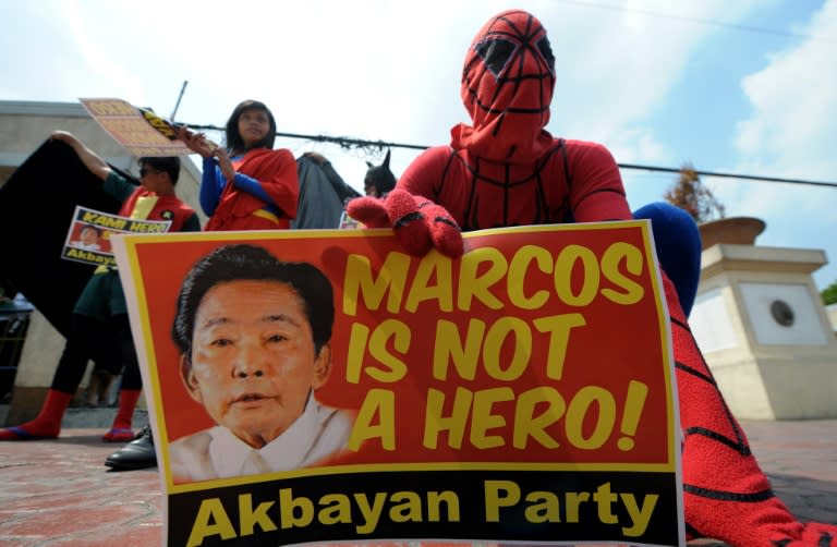 Activists wearing superhero costumes hold banners saying that the late Philippine dictator Ferdinand Marcos is not a hero, protesting the proposed dictator's hero burial in Manila on April 18, 2011