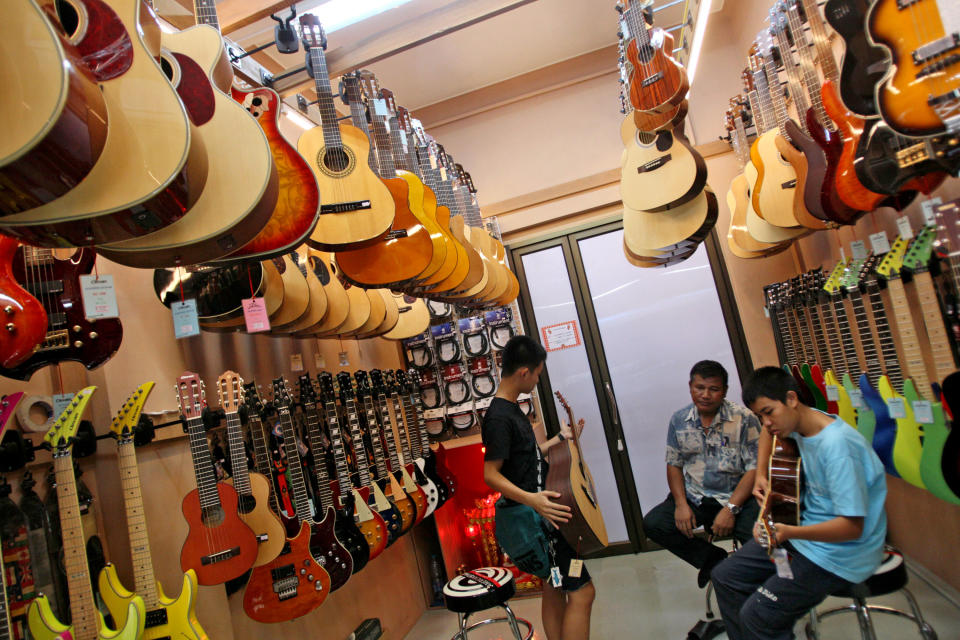 Customers check some guitars at a musical instrument shop in Bangkok, Thailand, Friday, March 8, 2013. Delegates attending a global biodiversity conference in Bangkok this week are debating a U.S. proposal to streamline international customs checks for travelers with musical instruments that legally contain endangered wildlife products like exotic hardwoods, ivory or tortoise shell. (AP Photo/Sakchai Lalit)