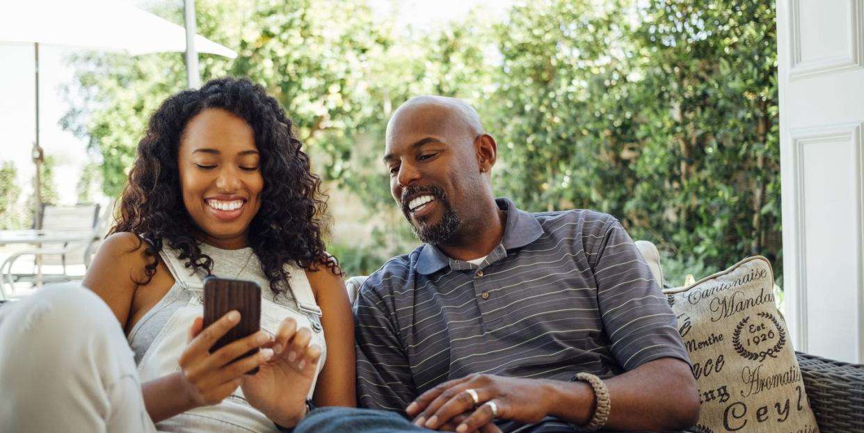 adult siblings looking at smart phone together in backyard