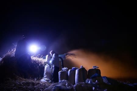 Farmers harvest wheat in a field at night, fearing shelling in daylight, in the rebel held besieged town of Douma, eastern Ghouta in Damascus, Syria early morning June 24, 2016. REUTERS/Bassam Khabieh