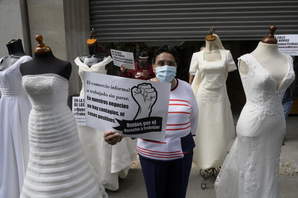 A vendor of dresses for brides and fifteen-year-olds holding a signal that reads "In our stores there are no infections or positive cases" protests with mannequins in the streets of downtown Mexico City, on January 11, 2021. - Vendors are demanding to be allowed to open their stores, since the city Government banned these stores in an effort to lower COVID-19 infections. (Photo by ALFREDO ESTRELLA / AFP) (Photo by ALFREDO ESTRELLA/AFP via Getty Images)