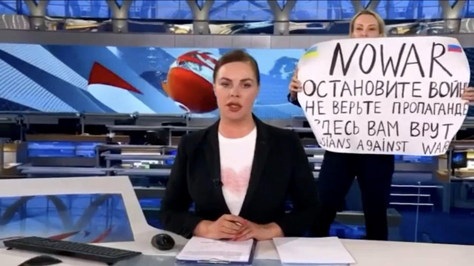 Marina Ovsyannikova stands behind a news anchor holding up an antiwar sign saying 