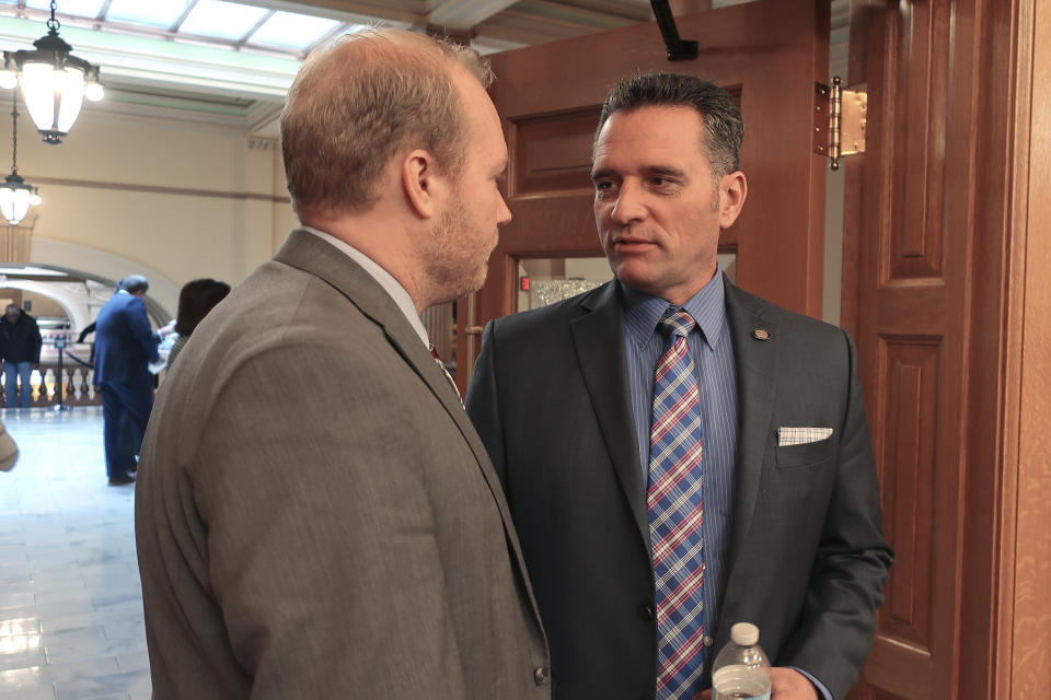 In this Wednesday, Feb. 19, 2020 photo, Will Lawrence, left, Kansas Gov. Laura Kelly's chief of staff, confers with Senate Utilities Committee Chairman Ty Masterson, right, R-Andover, before a hearing at the Statehouse in Topeka, Kan. Gov. Kelly has issued an executive order supported by environmentalists aimed at making the state's energy office more effective, but it's meeting resistance from some Republicans. (AP Photo/John Hanna)