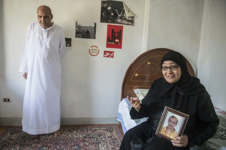 Reda Mahrous, holds a photo of her son, jailed Egyptian photographer Mahmoud Abdel Shakour Abou-Zeid, as her husband Abedel Shakour Abu Zeid looks on, at their home in Cairo