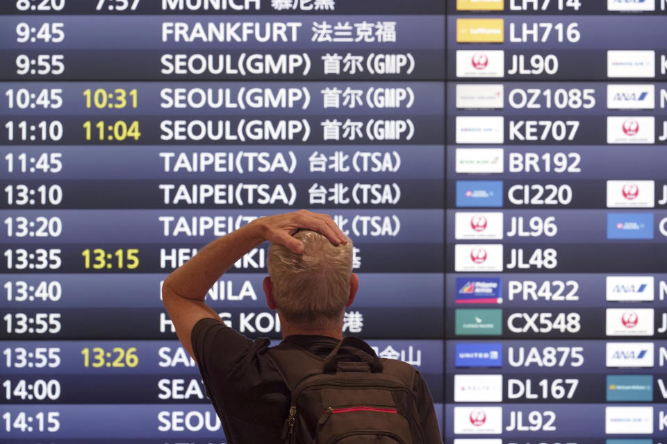 One of foreign travelers stands in front of a flight information board upon his arrival at the Haneda International Airport Tuesday, Oct. 11, 2022, in Tokyo. Japan's strict border restrictions are eased, allowing tourists to easily enter for the first time since the start of the COVID-19 pandemic. Independent tourists are again welcomed, not just those traveling with authorized groups. (AP Photo/Eugene Hoshiko)