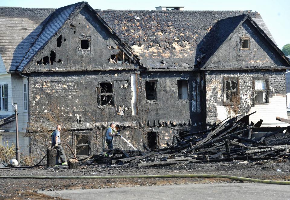 Investigators survey the scene of a 4-alarm fire at 2 Mann St. in Hingham where one home was destroyed and an adjacent house, pictured, was charred on Monday, July 11, 2022.