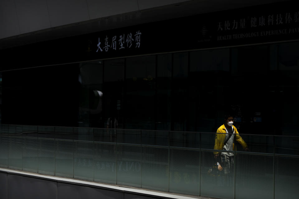 A delivery driver wearing a face mask walks through a shopping and office complex in Beijing, Thursday, June 30, 2022. (AP Photo/Mark Schiefelbein)