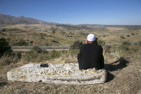 A member of the Druze community uses binoculars to watch the fighting in Syria, from the Israeli side of the border fence between Syria and the Israeli-occupied Golan Heights, near Majdal Shams June 18, 2015. REUTERS/Baz Ratner