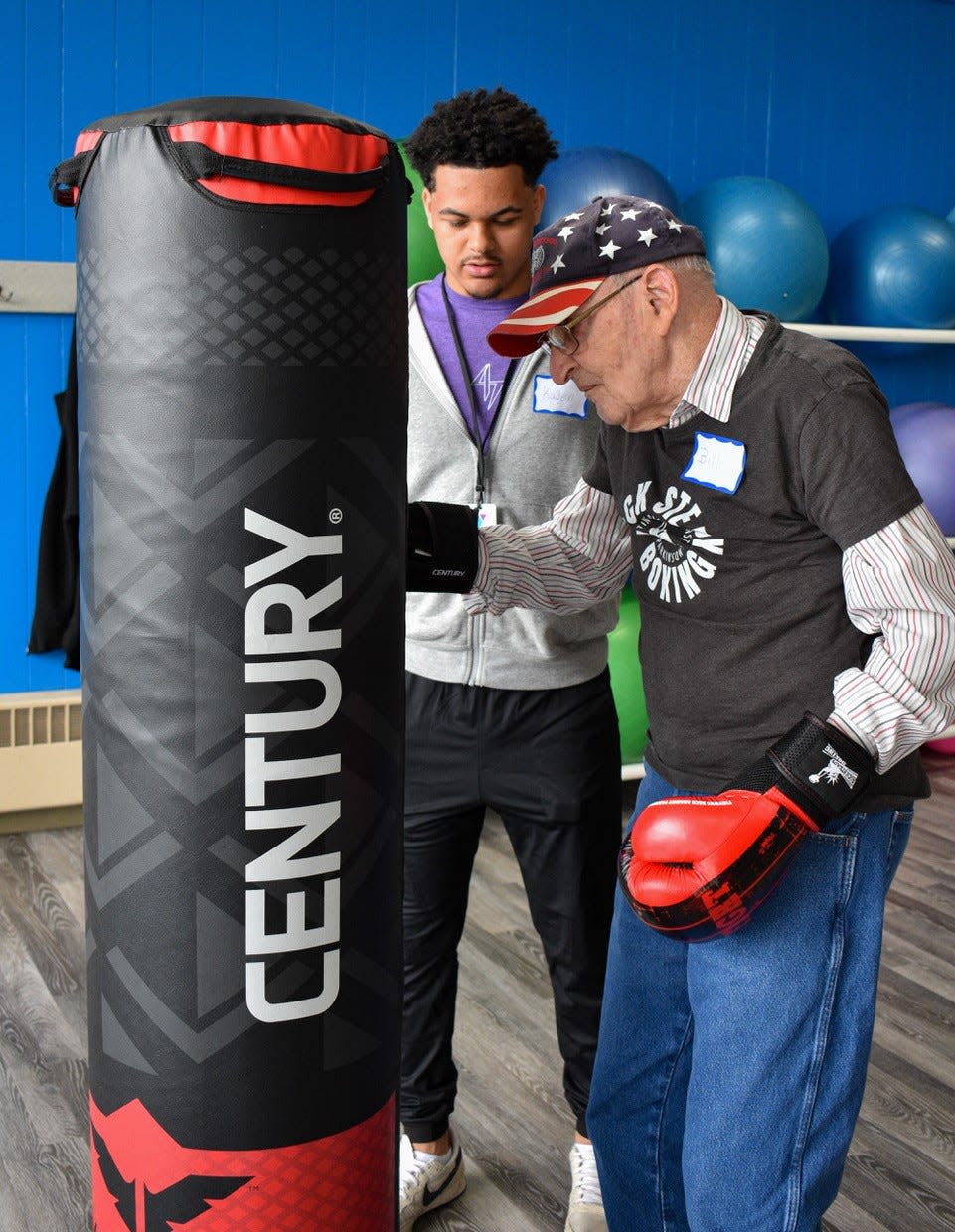 YMCA staffer Kaden Holmes assists Bill Heilman of Fremont during a Rock Steady Boxing class for people diagnosed with Parkinson’s disease.