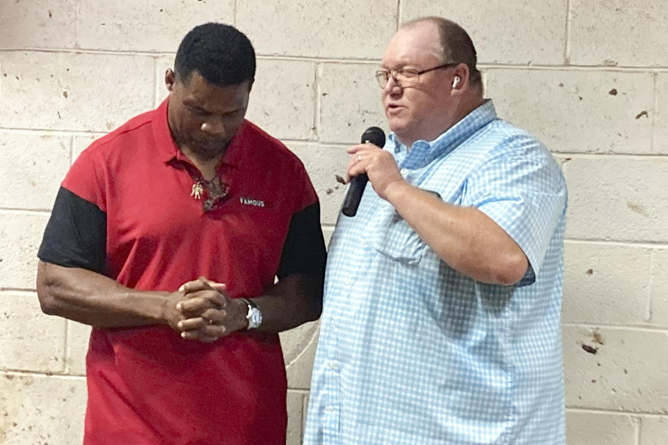 Georgia businessman Todd Stephens prays with Republicans U.S. Senate nominee Herschel Walker at Stephens’ livestock auction arena outside Athens, Ga., Wednesday, July 20, 2022, where Walker first came to fame as a star running back for the University of Georgia Bulldogs football team in 1980. Walker, an ally and personal friend of former President Donald Trump, is making his first run for public office as he tries to unseat Democratic Sen. Raphael Warnock. (AP Photo/Bill Barrow)