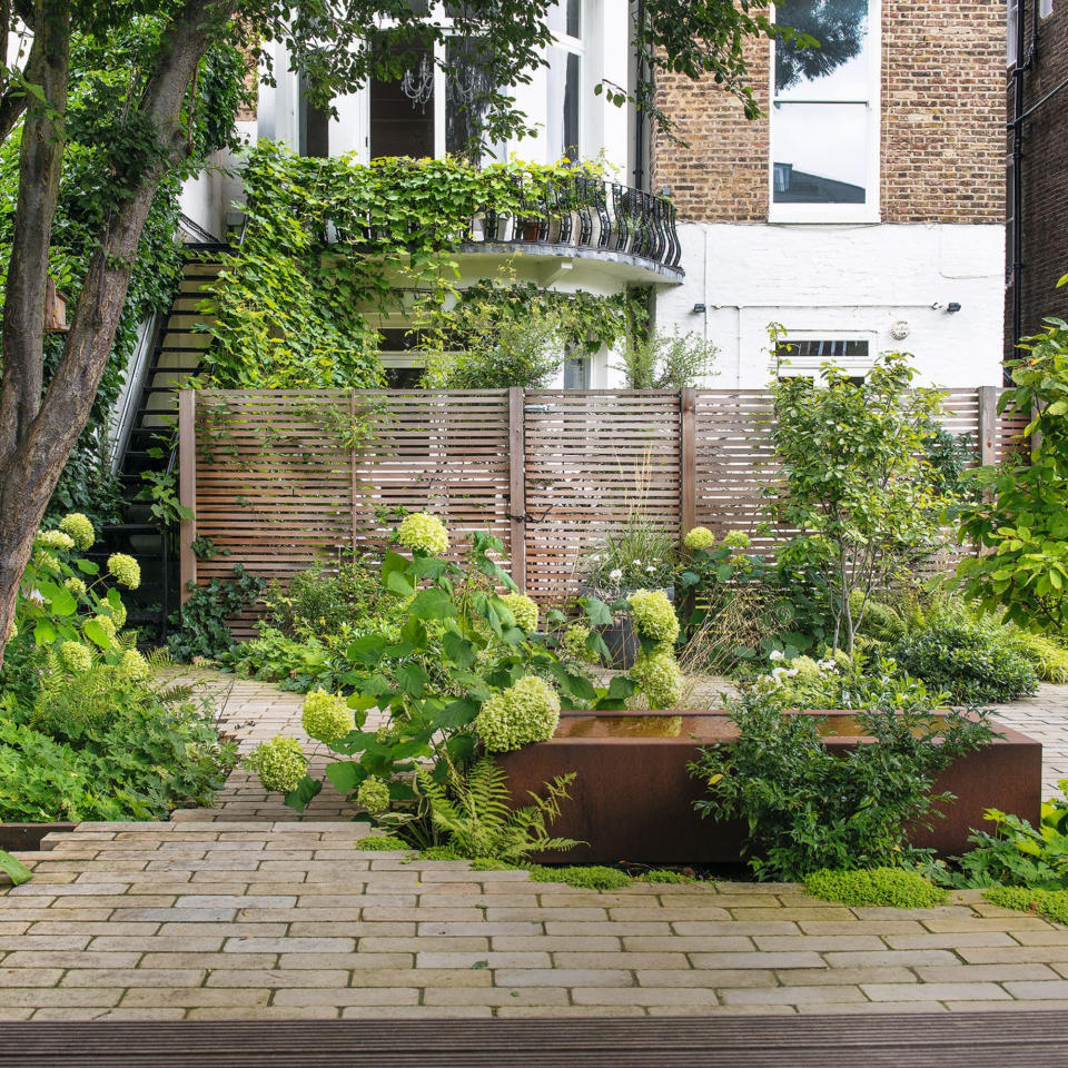 Patio area with hydrangea shrubs, water feature with house in the background