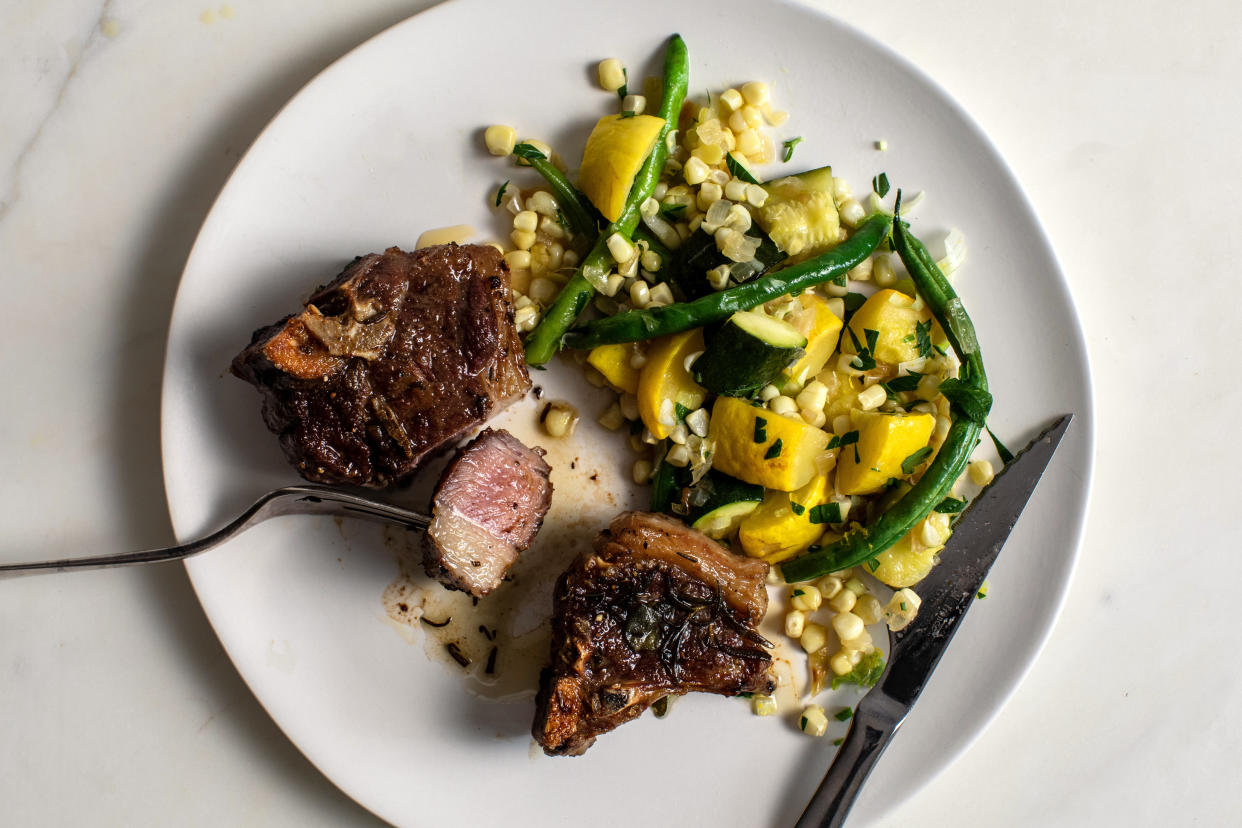 Chuletas de cordero fritas en sartén con ejotes, elote, calabacita y calabaza de verano, en Nueva York, el 29 de agosto de 2020. (Andrew Scrivani/The New York Times)