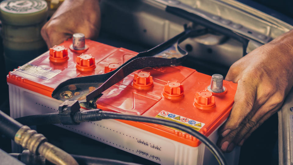 A car mechanic replaces a battery - Image.