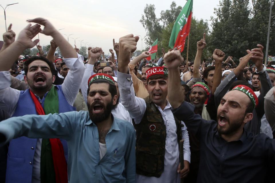 Supporters of former Pakistani Prime Minister Imran Khan's party, 'Pakistan Tehreek-e-Insaf' chant slogans while they block a highway during a protest to condemn a shooting incident on their leader's convoy, in Peshawar, Pakistan, Friday, Nov. 4, 2022. Khan who narrowly escaped an assassination attempt on his life the previous day when a gunman fired multiple shots and wounded him in the leg during a protest rally is listed in stable condition after undergoing surgery at a hospital, a senior leader from his party said Friday. (AP Photo/Muhammad Sajjad)