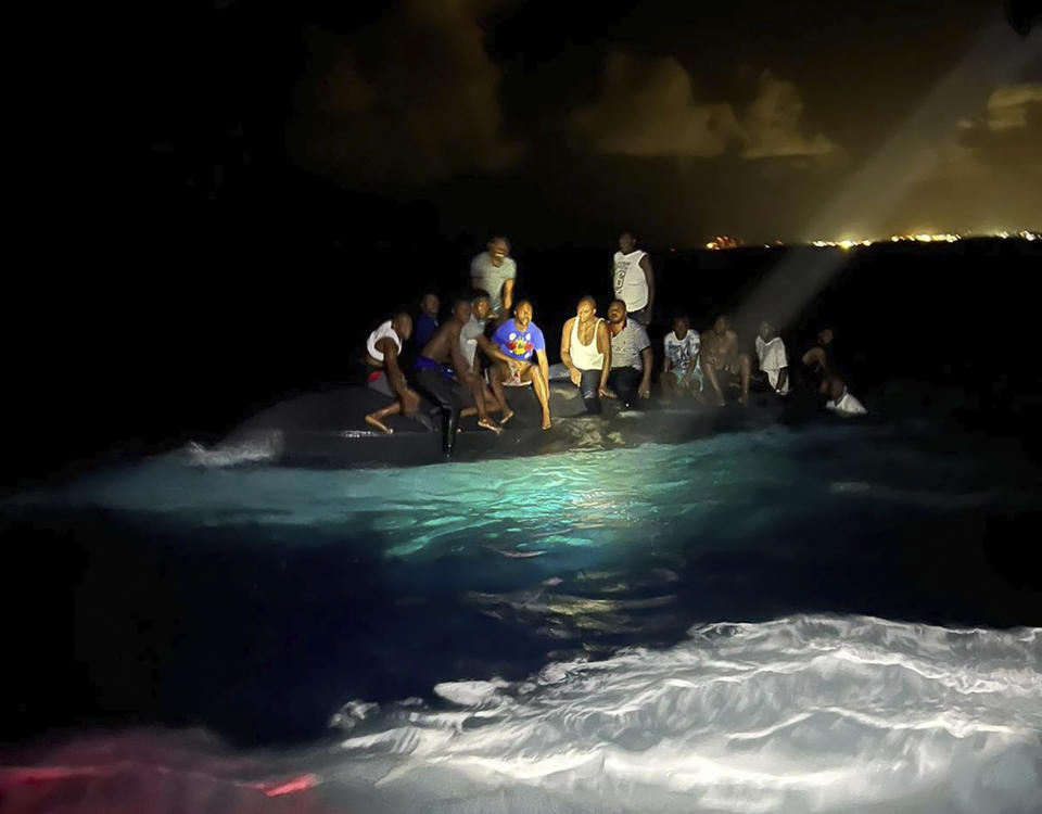 Survivors sit on a capsized boat as they are about to be rescued near New Providence in the Bahamas, early Sunday. (Royal Bahamas Defense Force via AP)