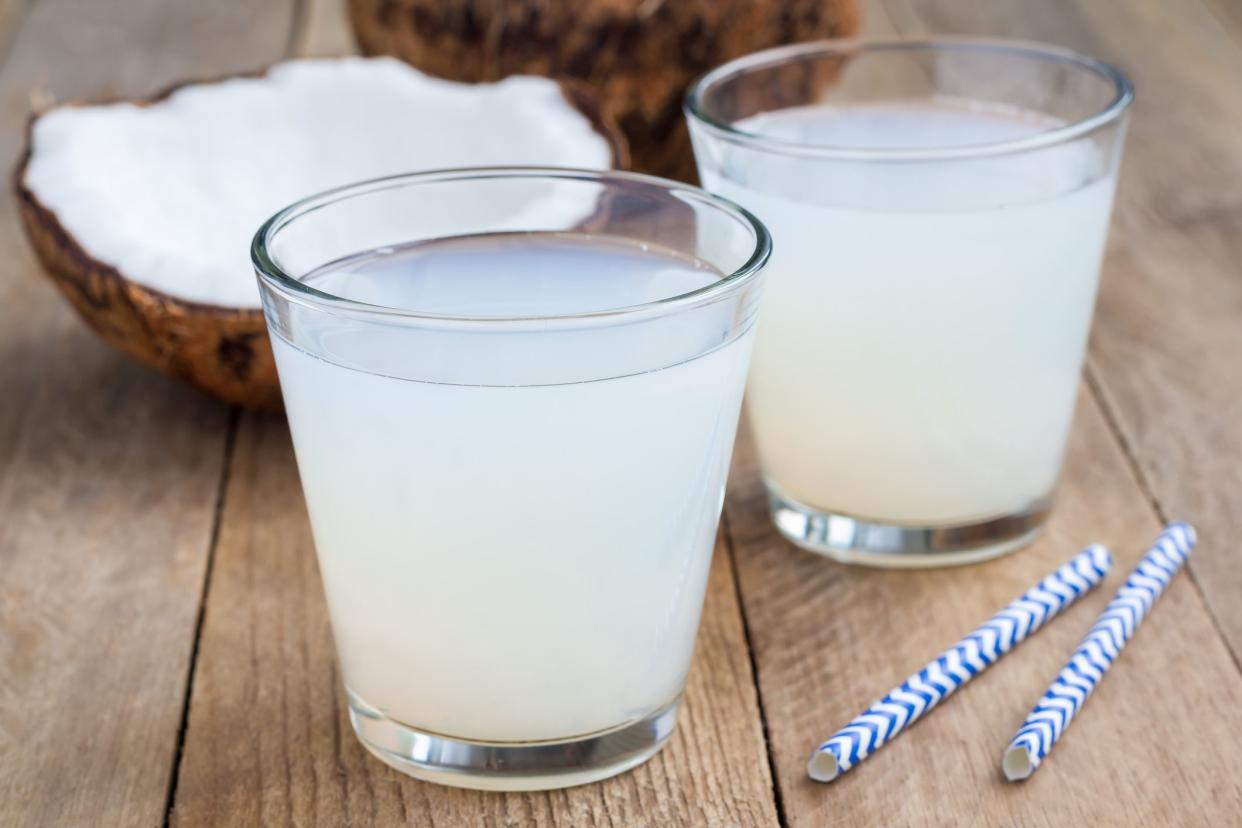 Coconut drink with pulp in a glass on a wooden table