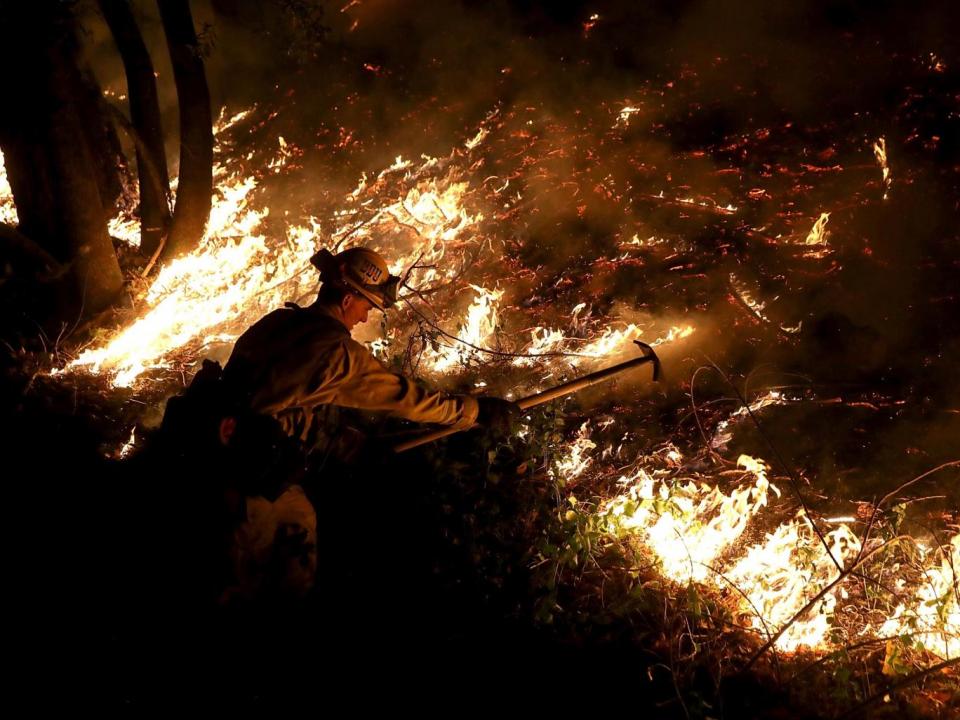 A firefighter using a hand tool as he monitors a firing operation while a fire near Calistoga, California (Justin Sullivan/Getty Images)