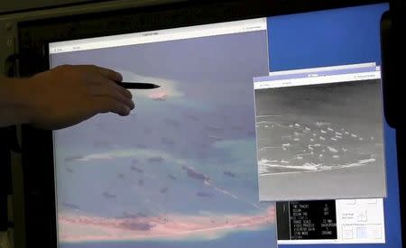 A U.S. Navy crewman aboard a P-8A Poseidon surveillance aircraft points to a computer screen purportedly showing Chinese construction on the reclaimed land of Fiery Cross Reef in the disputed Spratly Islands in the South China Sea in this still image from video provided by the United States Navy on May 21, 2015. REUTERS/U.S. Navy/Handout via Reuters/Files