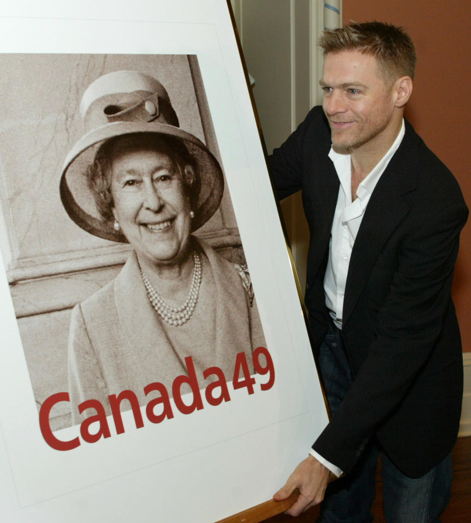 Bryan Adams holds a large replica of a new stamp honoring Queen Elizabeth II at a 2003 ceremony Ottawa, Canada. (Photo: Reuters/Jim Young)