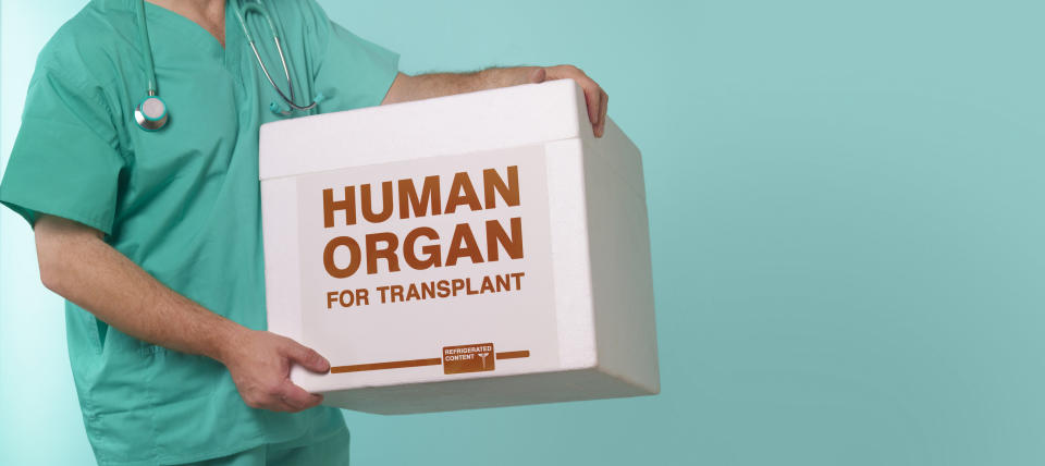 a person in scrubs holding a box labeled "human organ for transplant"