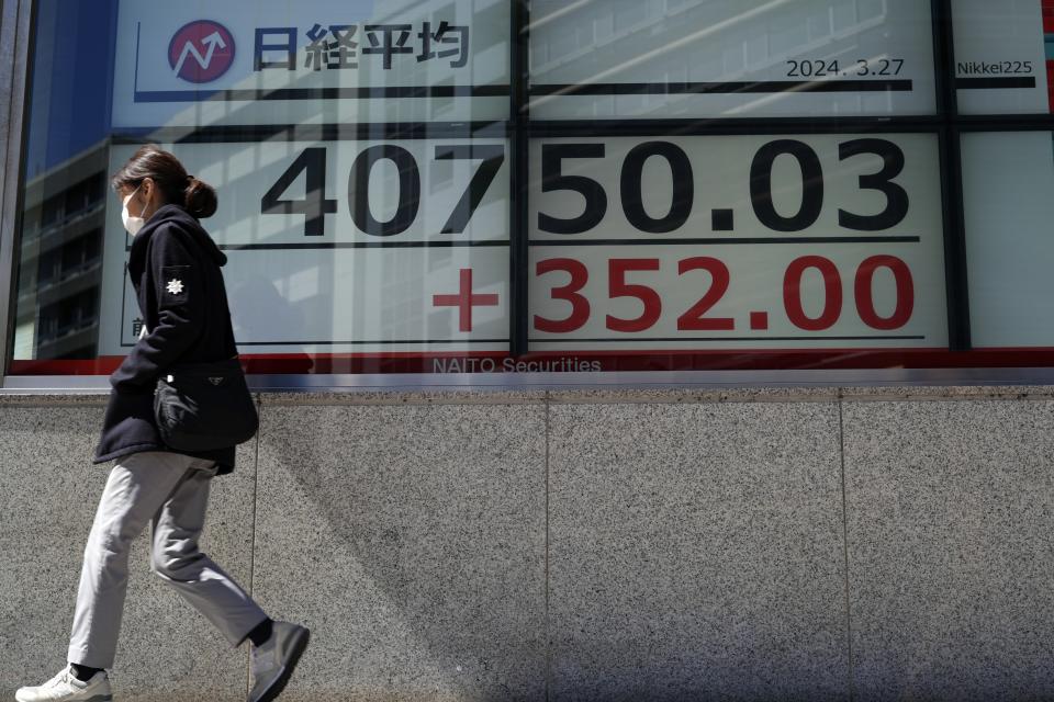 A person walks in front of an electronic stock board showing Japan's Nikkei 225 index at a securities firm Wednesday, March 27, 2024, in Tokyo. Asian shares were mixed on Wednesday after Wall Street slipped a bit further from its record highs.(AP Photo/Eugene Hoshiko)