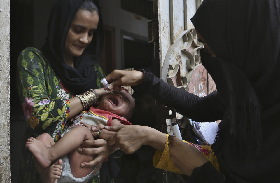 A health worker administers a polio vaccine to a child, in Karachi, Pakistan, Wednesday, June 9, 2021. Gunmen on a motorcycle Wednesday shot and killed two police officers assigned to protect polio vaccination workers in the district of Mardan in Khyber Pakhtunkhwa province, northwest Pakistan before fleeing, police said. (AP Photo/Fareed Khan)