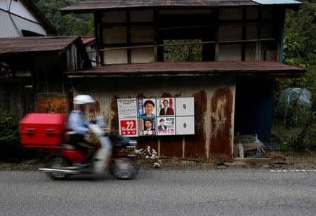 A postman rides a motorbike past candidates' posters for the October 22 lower house election in front of a desolate old house in Nanmoku Village, northwest of Tokyo, Japan October 12, 2017. Picture taken October 12, 2017. REUTERS/Issei Kato