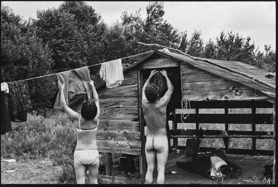 A couple hanging clothes out to dry on a hillside away from the crowd at Woodstock, in 1969. | Burk Uzzle