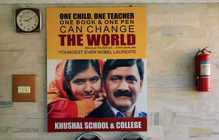 A poster with the pictures of Nobel Peace Prize winner Malala Yousafzai and her father Ziauddin Yousufzai hangs at the wall of Khushal School, in her home district in Swat Valley, Pakistan March 30, 2018. REUTERS/Faisal Mahmood