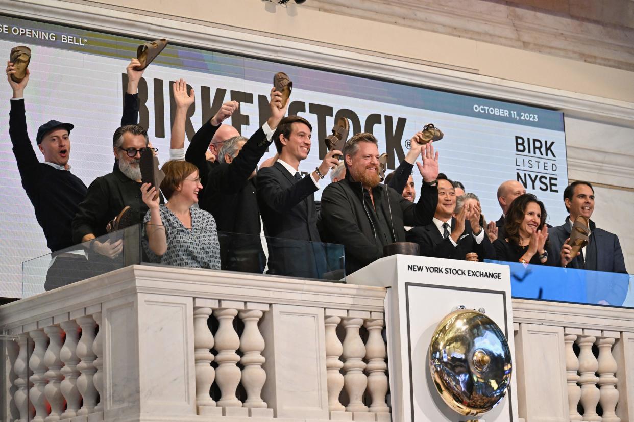 Birkenstock CEO Oliver Reichert (C) waves as he rings the opening at New York Stock Exchange (NYSE) New York on October 11, 2023, during Birkenstock's launch of an Initial Public Offering (IPO). German sandals maker Birkenstock has set its share price at $46, the firm said in a press release early Wednesday. A total of 32.26 million ordinary shares will be offered in its initial public offering, trading under the symbol BIRK. (Photo by ANGELA WEISS / AFP) (Photo by ANGELA WEISS/AFP via Getty Images)