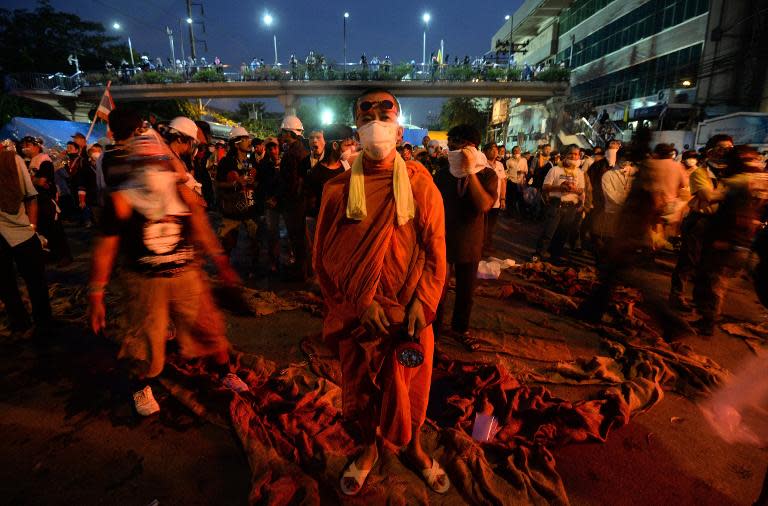 A Buddhist monk wearing a face mask stands along with volunteers near the Government house during ongoing anti-government demonstrations in Bangkok on December 2, 2013