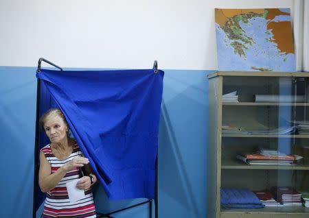 A woman exits a voting booth holding her ballot next to a map of Greece before voting in a general election at a polling station in Athens, Greece, September 20, 2015. REUTERS/Alkis Konstantinidis