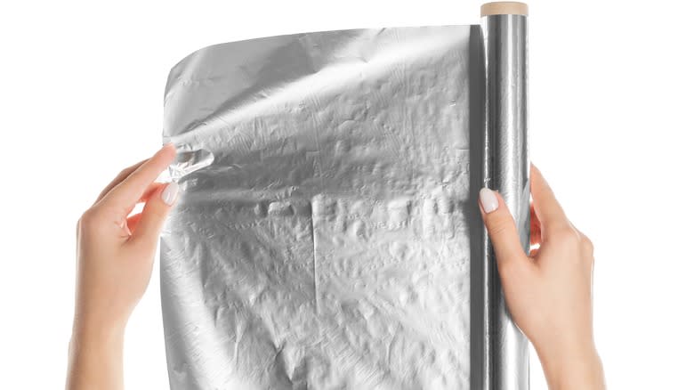Person pulling aluminum foil from roll