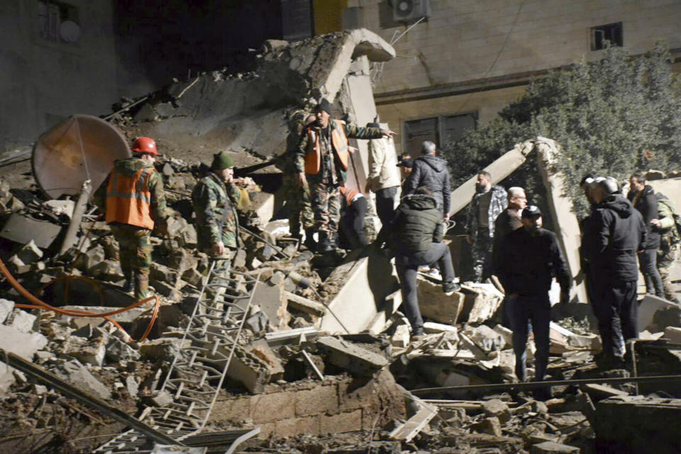 In this photo released by the Syrian official news agency SANA, Syrian security forces gather near the rubble of a building that was destroyed by Israeli airstrikes, in Homs, Syria, late Tuesday, Feb. 6, 2024. Syria's military says Israeli airstrikes over the central city of Homs and nearby areas have killed and wounded civilians. (SANA via AP)