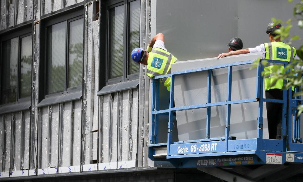 Workers remove cladding for testing at a tower block in Salford.